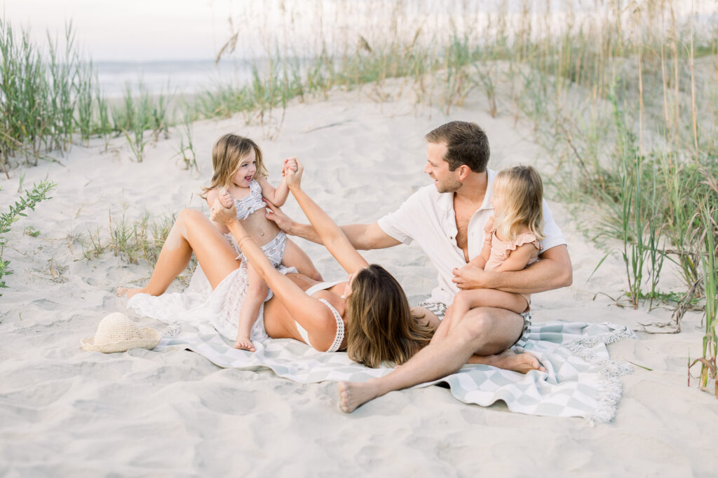 Family of 4 playing in the sand at the beach during a family photography session in Charleston South Carolina