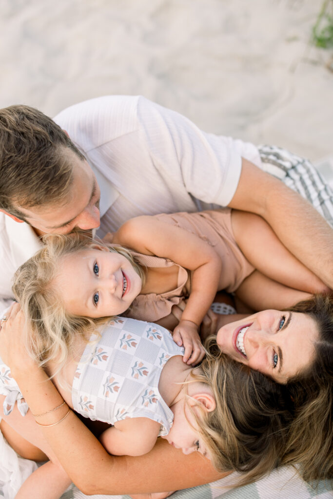 Mom and family snuggled up on the beach during a family session in Charleston South Carolina