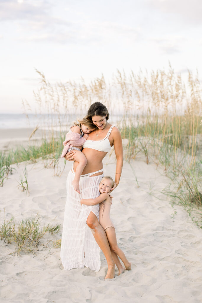 Mom and daughters snuggled at the beach in Charleston South Carolina during a family session 