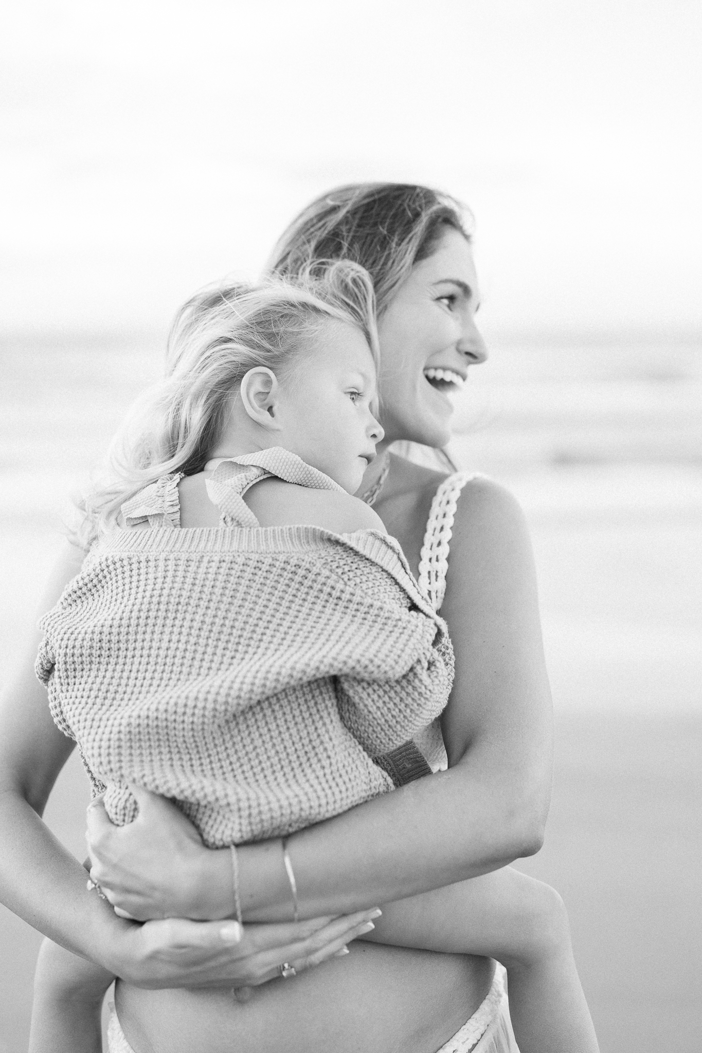 black and white image at a beach, mom holding daughter at a family session in Charleston