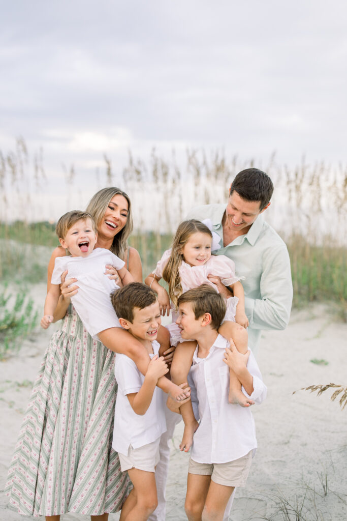 family memers stacked on top of each other at the beach during a family session in Charleston South Carolina