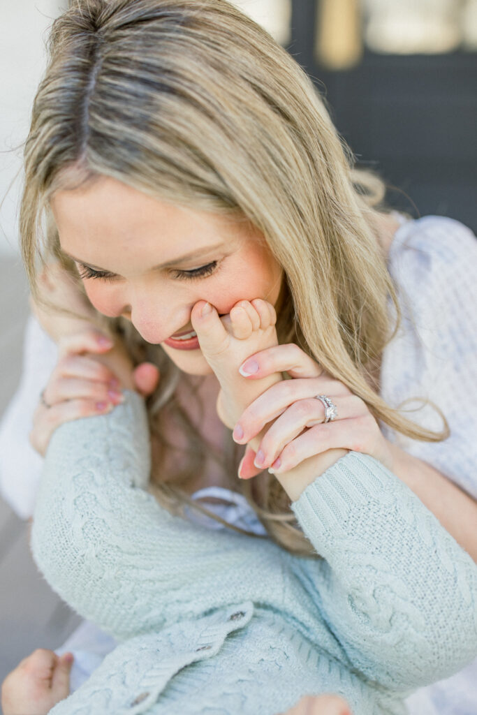 baby's toes on mothers cheek, mom smiling big during a mothers day photo session in Tomball 